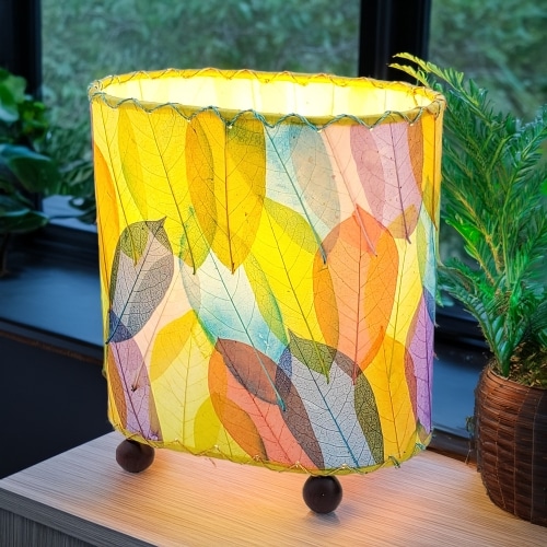 Crafted by the artisans of Eangee Home Design, the Mini Guyabano Table Lamp in multi color against a clean backdrop, featuring fossilized cocoa leaf shade, guyabano leaf shade, wrought iron frame.