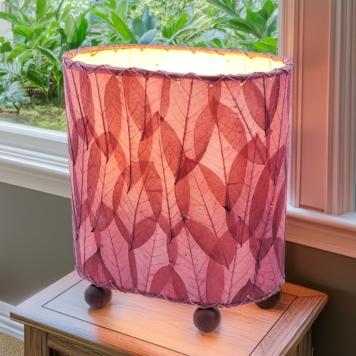 In a modern interior with earth tones, crafted by the artisans of Eangee Home Design, the Mini Guyabano Table Lamp in purple stands gracefully, featuring fossilized cocoa leaf shade, guyabano leaf shade, wrought iron frame, adding warmth and character to the space.