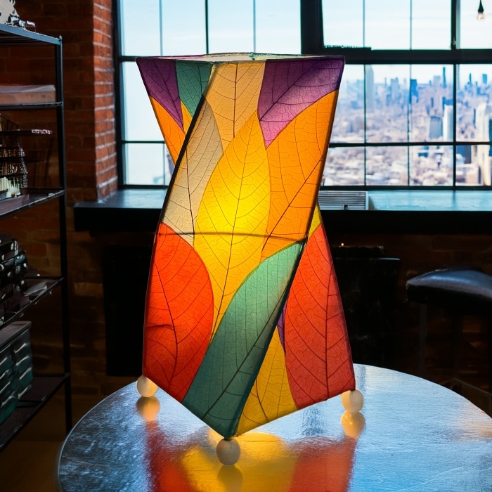 In a sun drenched entryway, crafted by the artisans of Eangee Home Design, the Twist Table Lamp in multi color stands gracefully, featuring fossilized cocoa leaf shade, wrought iron frame, handcrafted, adding warmth and character to the space.
