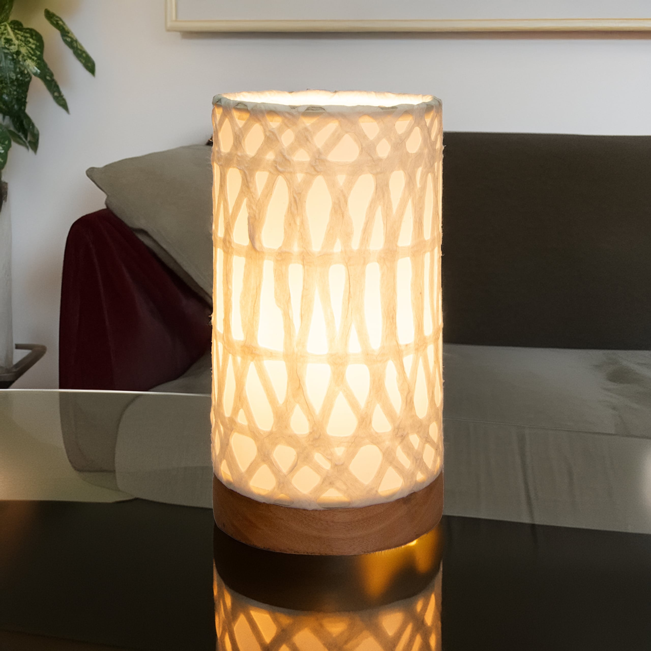 In a coastal inspired living room, crafted by the artisans of Eangee Home Design, the Mini Paper Cylinder Table Lamp Arches in natural stands gracefully, featuring reclaimed mango wood base, recycled paper shade, sustainably sourced, recycled materials, adding warmth and character to the space.
