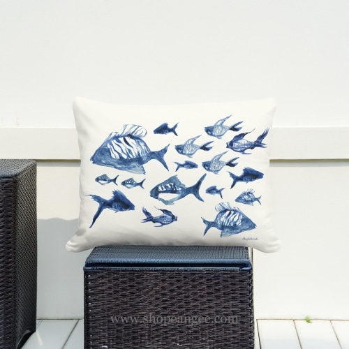 In an outdoor reading nook a multi colored outdoor pillow crafted by the artisans of Magnolia Casual called the Outdoor Pillow Underwater Ballet 19x24 is displayed featuring quality outdoor fabric adding comfort and style to the space.
