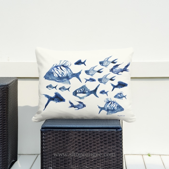 In an outdoor reading nook a multi colored outdoor pillow crafted by the artisans of Magnolia Casual called the Outdoor Pillow Underwater Ballet 19x24 is displayed featuring quality outdoor fabric adding comfort and style to the space.