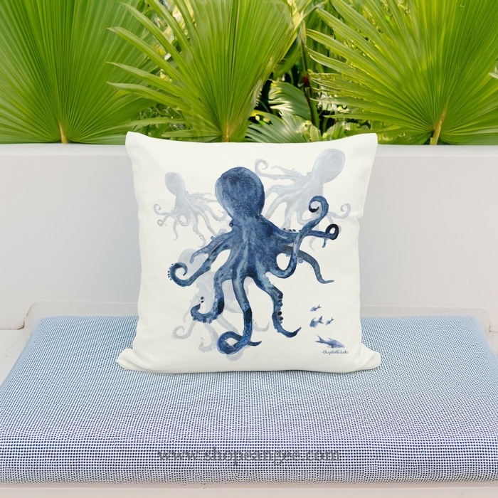 In a coastal inspired deck chair a multi colored outdoor pillow crafted by the artisans of Magnolia Casual called the Outdoor Pillow Indigo Octopus 18x18 is displayed featuring quality outdoor fabric adding comfort and style to the space featuring with a octopus motif.