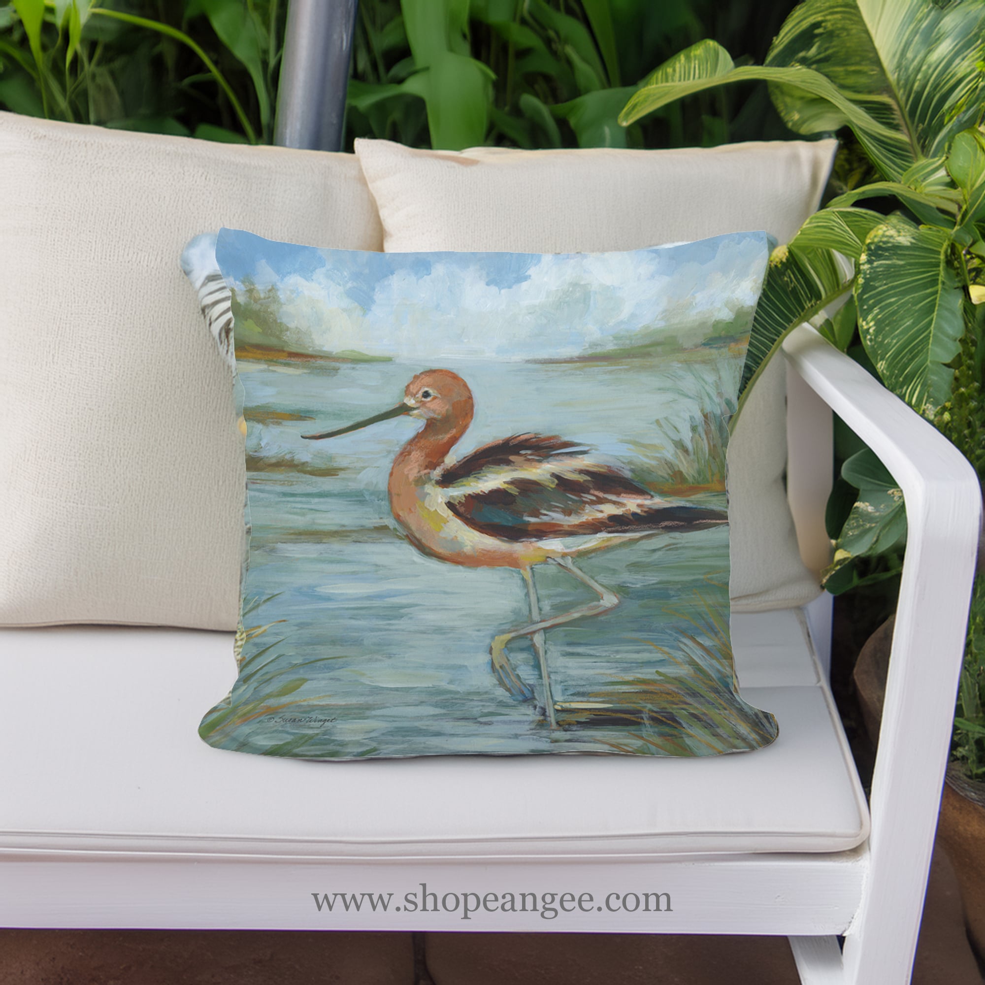 In a poolside chaise a multi colored outdoor pillow crafted by the artisans of Magnolia Casual called the Outdoor Pillow Avocet Bird in Water 18x18 is displayed featuring quality outdoor fabric, natural materials adding comfort and style to the space featuring with a bird motif.