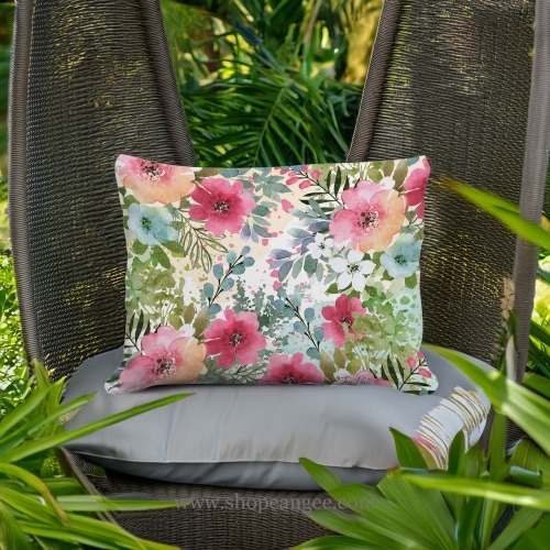 In a coastal inspired deck chair a multi colored outdoor pillow crafted by the artisans of Magnolia Casual called the Outdoor Pillow Meadow Dance 1 13x18 is displayed featuring 100 percent weather resistant fabric adding comfort and style to the space.