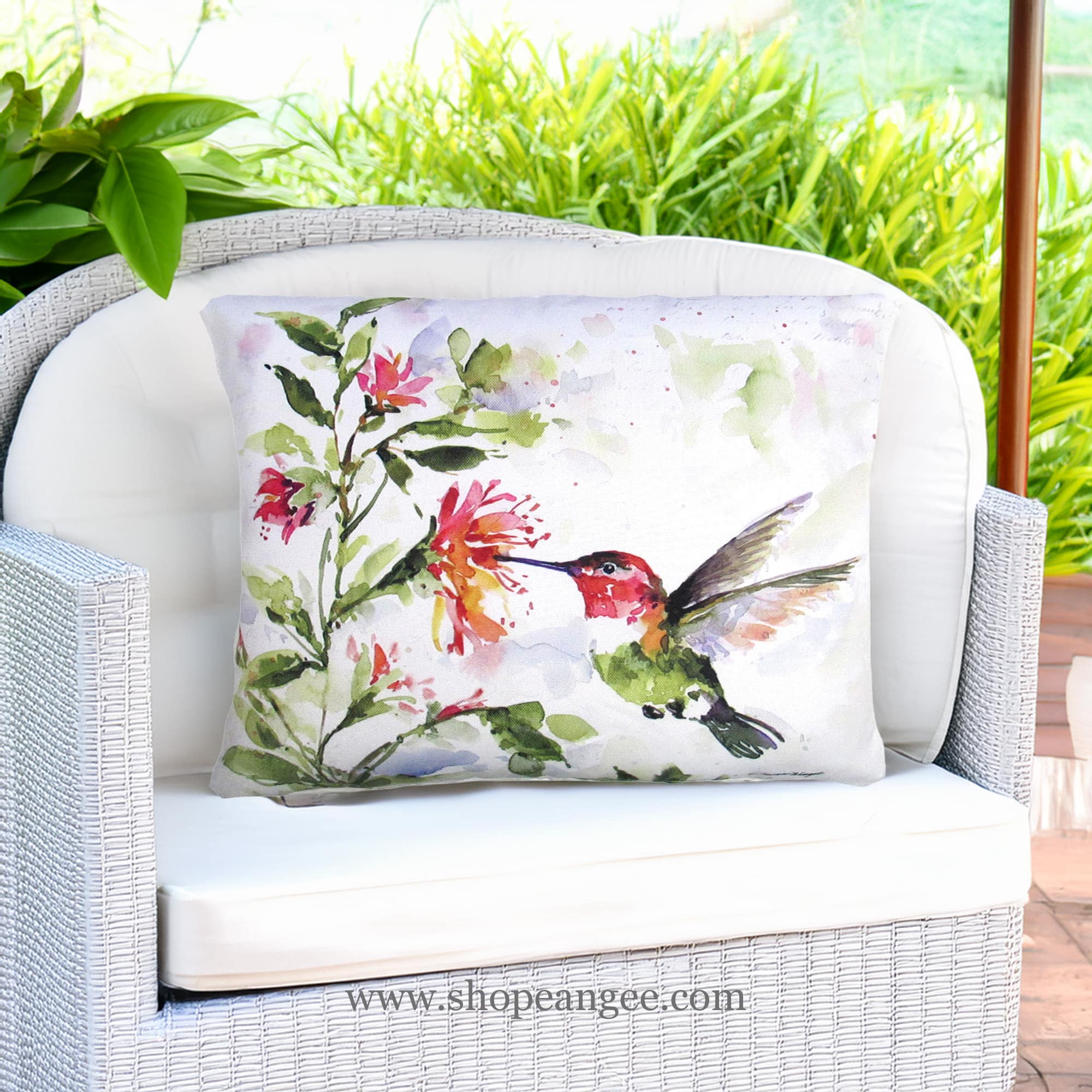In a poolside chaise a multi colored outdoor pillow crafted by the artisans of Magnolia Casual called the Outdoor Pillow Hummer w/Hanging Plant 2 19x24 is displayed featuring quality outdoor fabric adding comfort and style to the space.