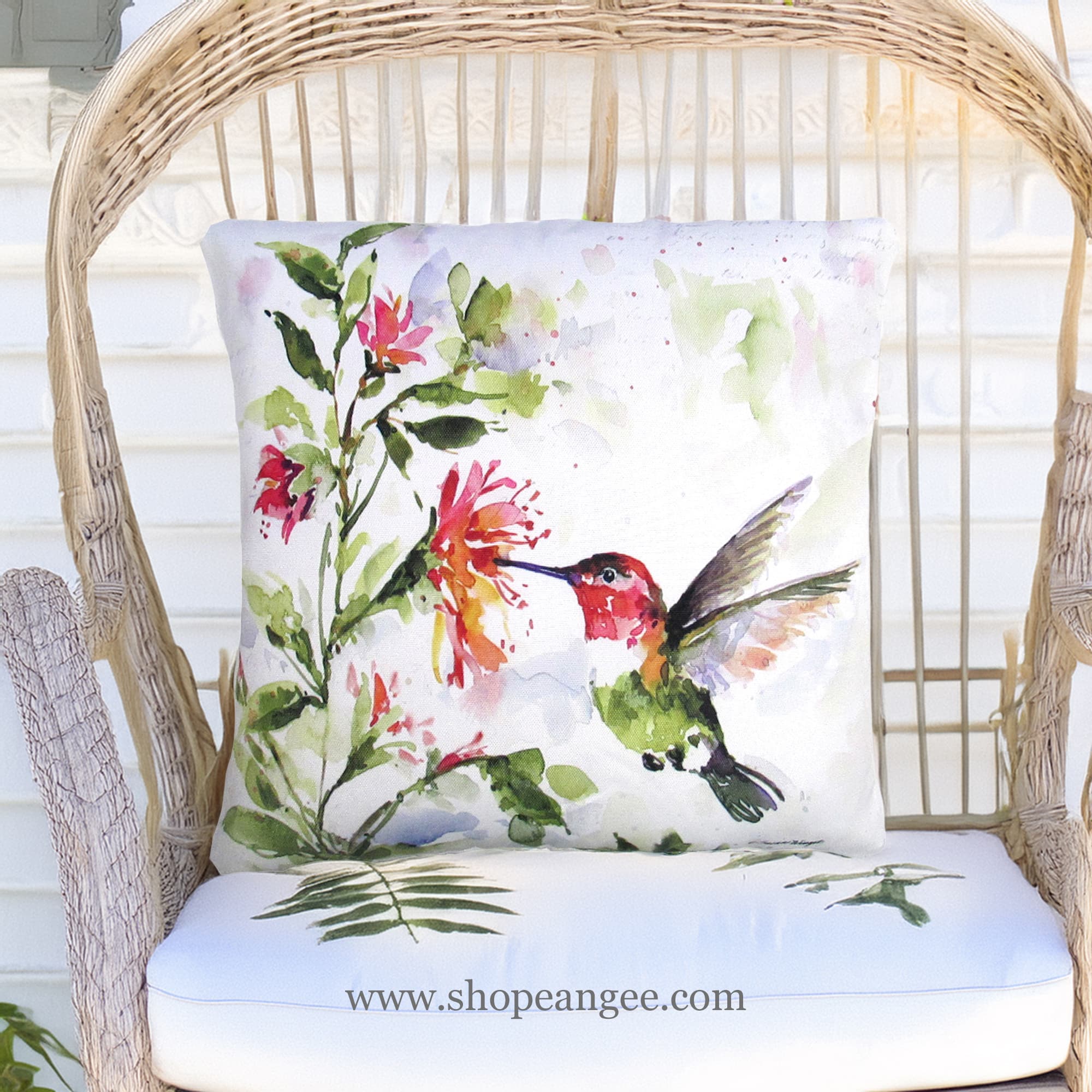 In a shaded porch swing a multi colored outdoor pillow crafted by the artisans of Magnolia Casual called the Outdoor Pillow Hummer w/Hanging Plant 2 18x18 is displayed featuring quality outdoor fabric adding comfort and style to the space.