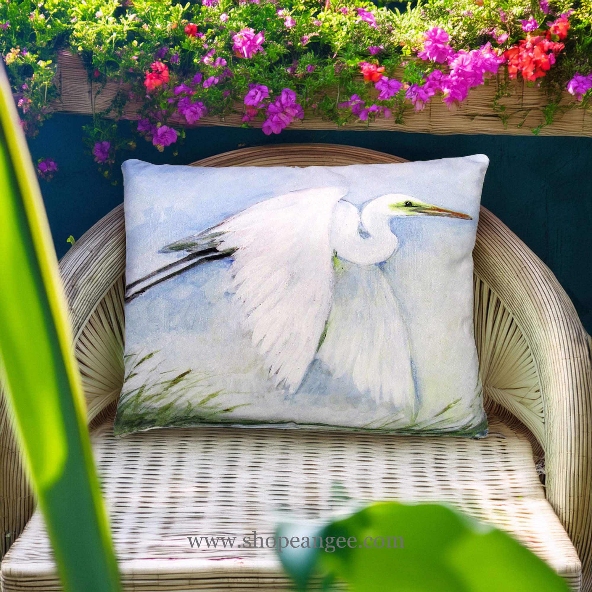 In a sunlit patio lounge a white outdoor pillow crafted by the artisans of Magnolia Casual called the Outdoor Pillow White Egret Flying 19x24 is displayed featuring quality outdoor fabric adding comfort and style to the space featuring shades of white.
