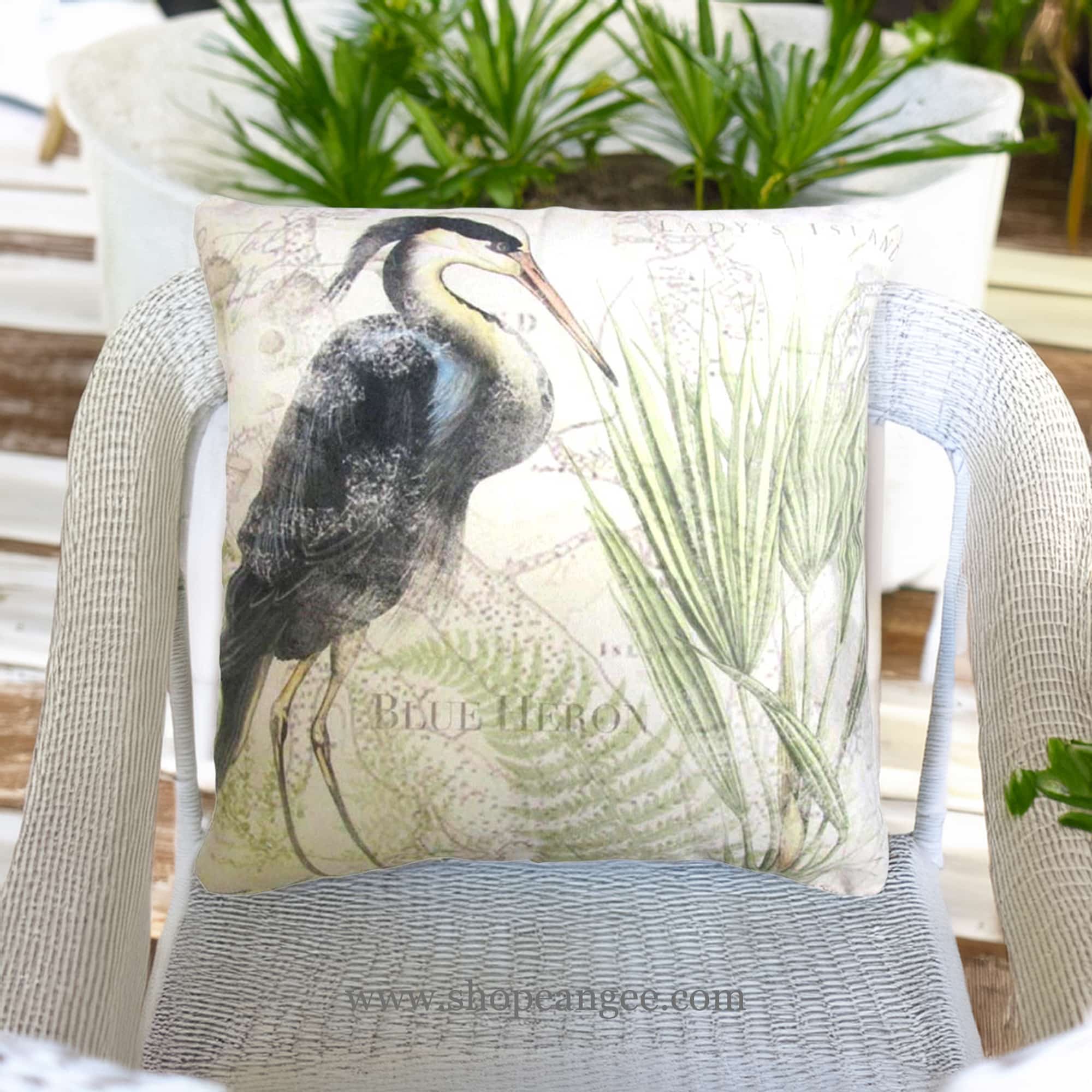 In a cozy garden seating area a multi colored outdoor pillow crafted by the artisans of Magnolia Casual called the Outdoor Pillow Great Heron 1 18x18 is displayed featuring quality outdoor fabric, natural materials adding comfort and style to the space.