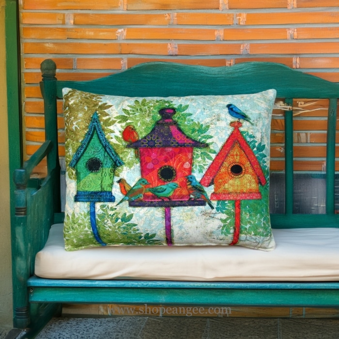 In a poolside chaise a multi colored outdoor pillow crafted by the artisans of Magnolia Casual called the Outdoor Pillow 3 Birdhouses 19x24 is displayed featuring quality outdoor fabric adding comfort and style to the space.