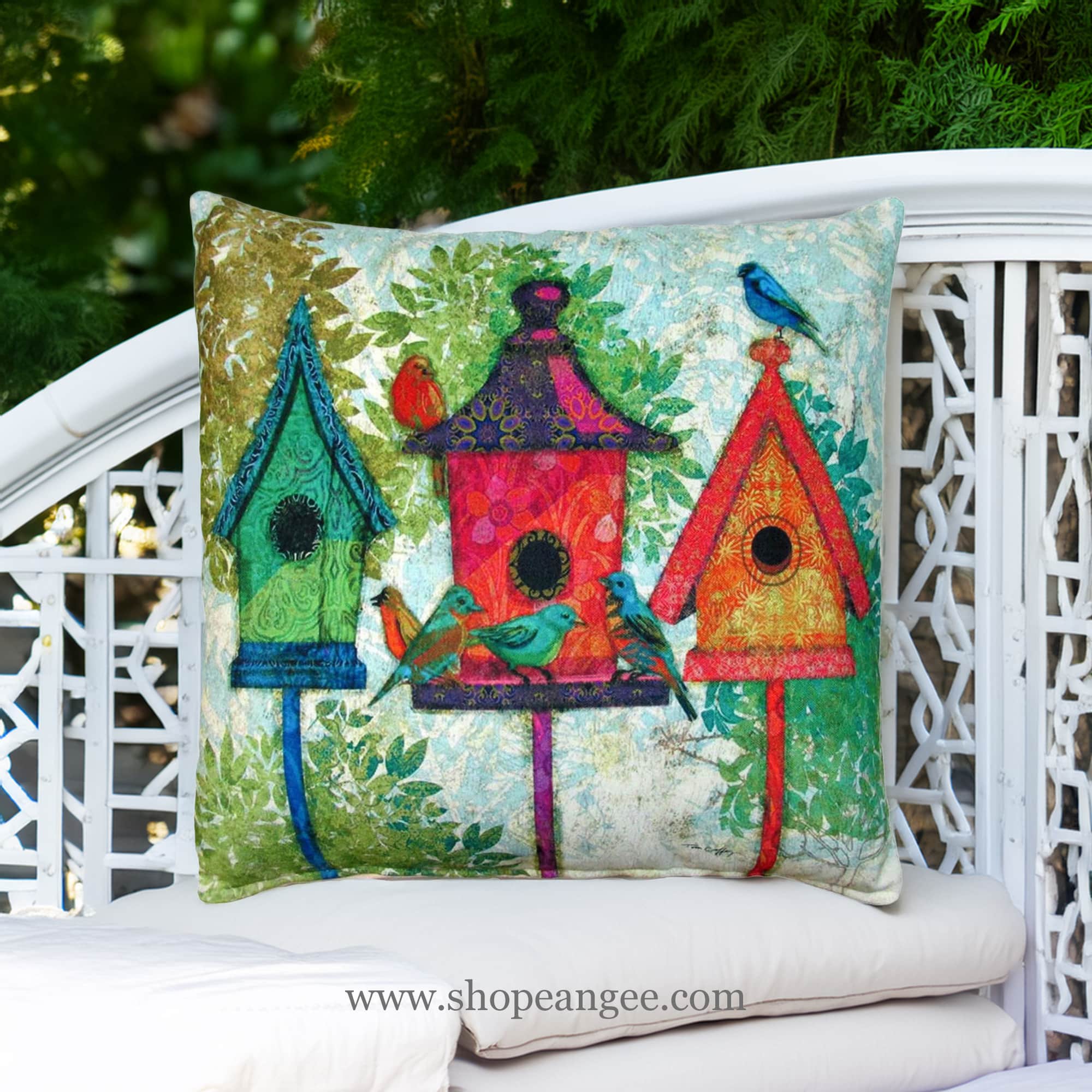In a sunlit patio lounge a multi colored outdoor pillow crafted by the artisans of Magnolia Casual called the Outdoor Pillow 3 Birdhouses 18x18 is displayed featuring quality outdoor fabric adding comfort and style to the space.