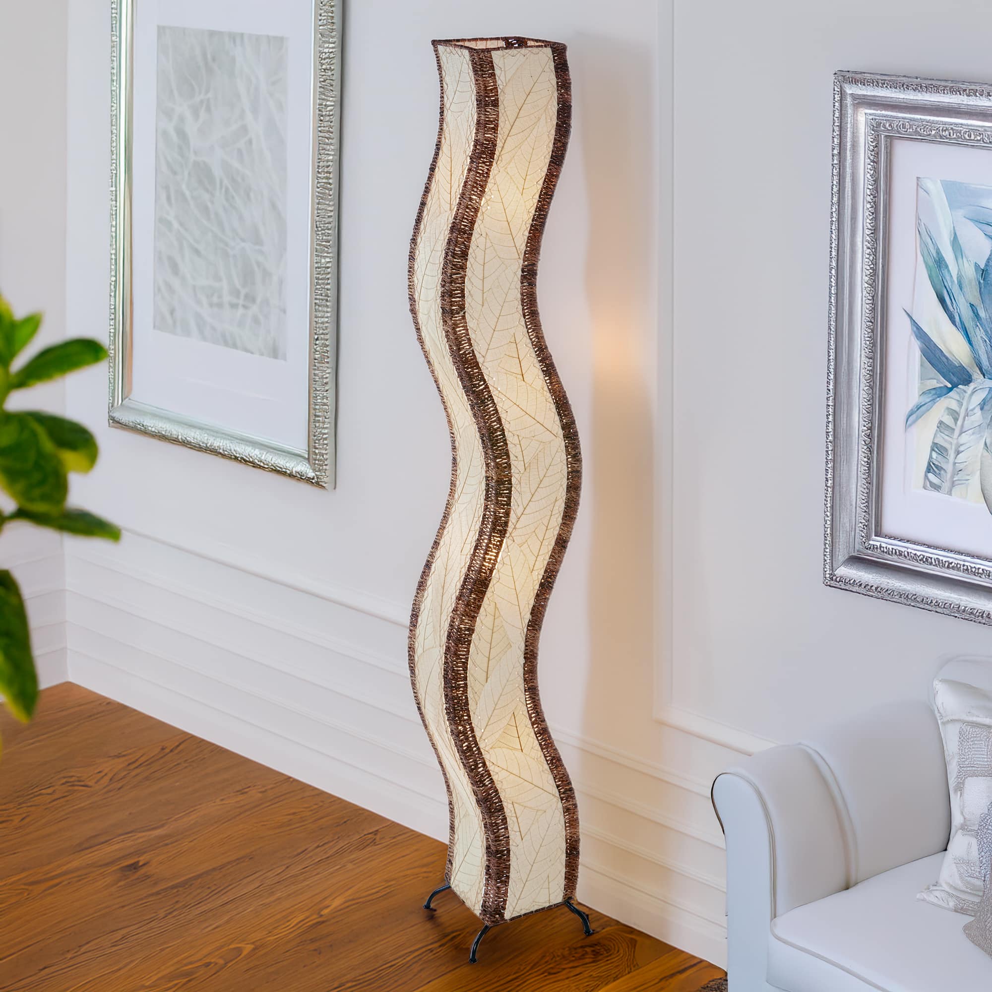 Natural Wave Giant Floor Lamp by Eangee Home Design - graceful wave form covered in neutral cocoa leaf panels and abaca trim; diffuses warm organic light, adding subtle movement beside contemporary artwork.