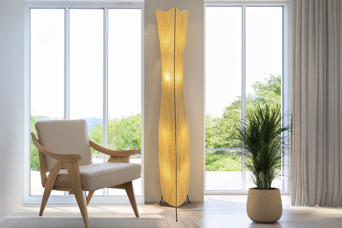 A tall floor lamp sits by chair and plant in front of windows.